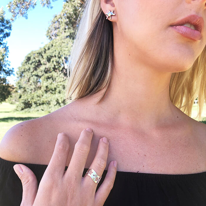 flat silver adjustable ring with star shaped cutouts on model