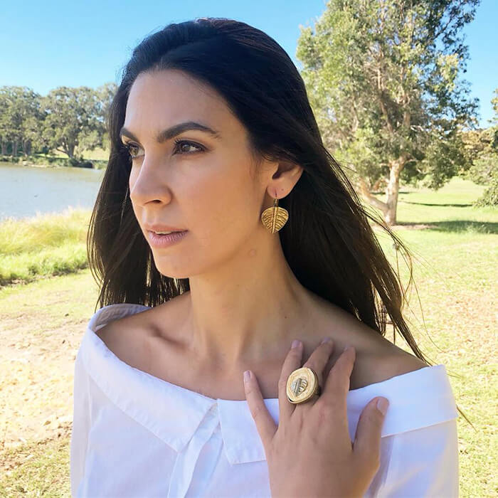 large statement ring and leaf shaped earrings on model